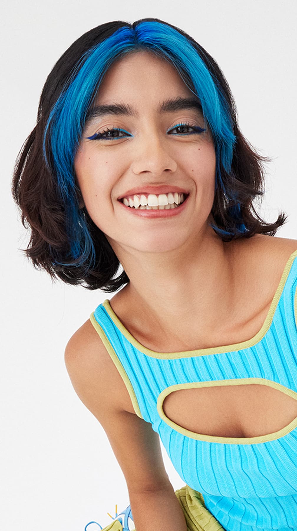 Young woman smiling, featuring Arctic Fox's Aquamarine hair color highlights, adding a pop of vivid blue to her natural dark hair.